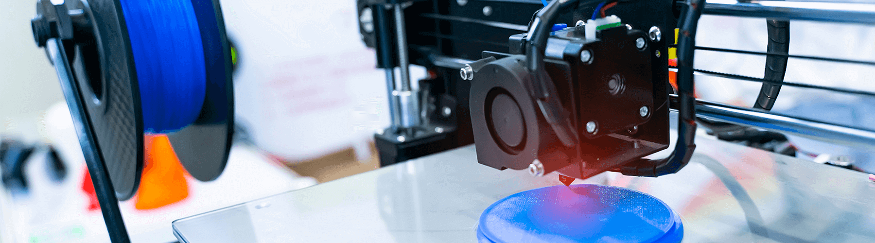 Ein 3D-Drucker erstellt ein blaues, rundes Objekt auf einer glatten Plattform.